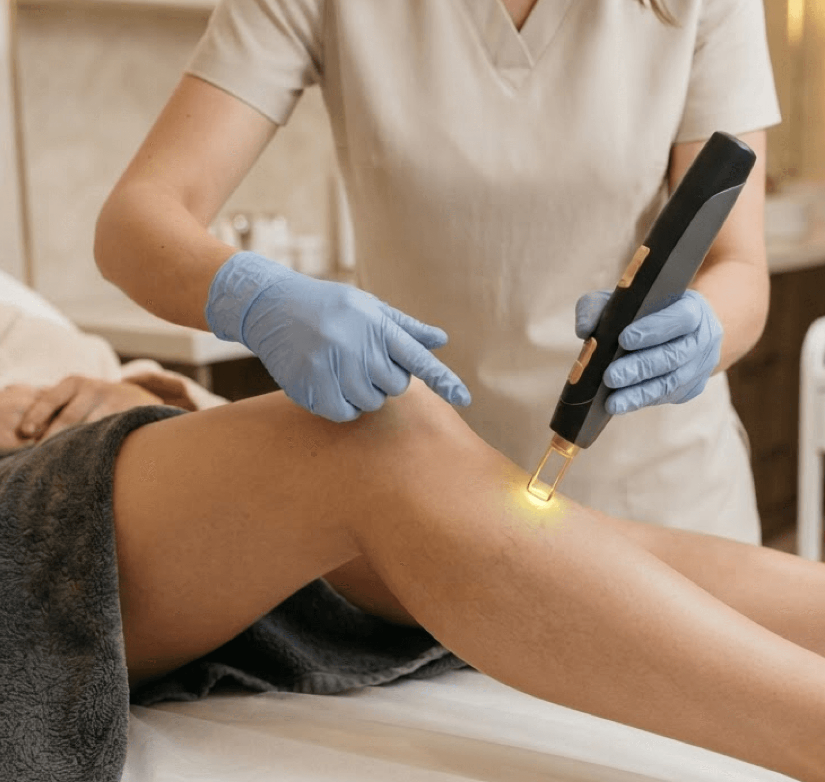 A clinician applying a vascular laser handpiece to a patient's knee in a bright treatment room