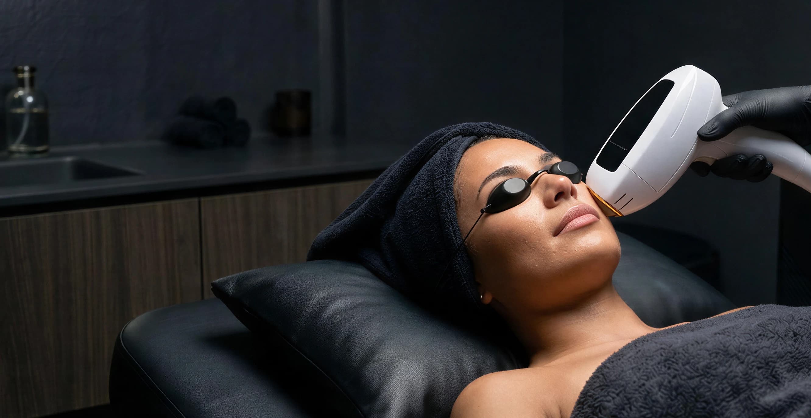A patient wearing protective goggles receiving a laser hair removal treatment on the face