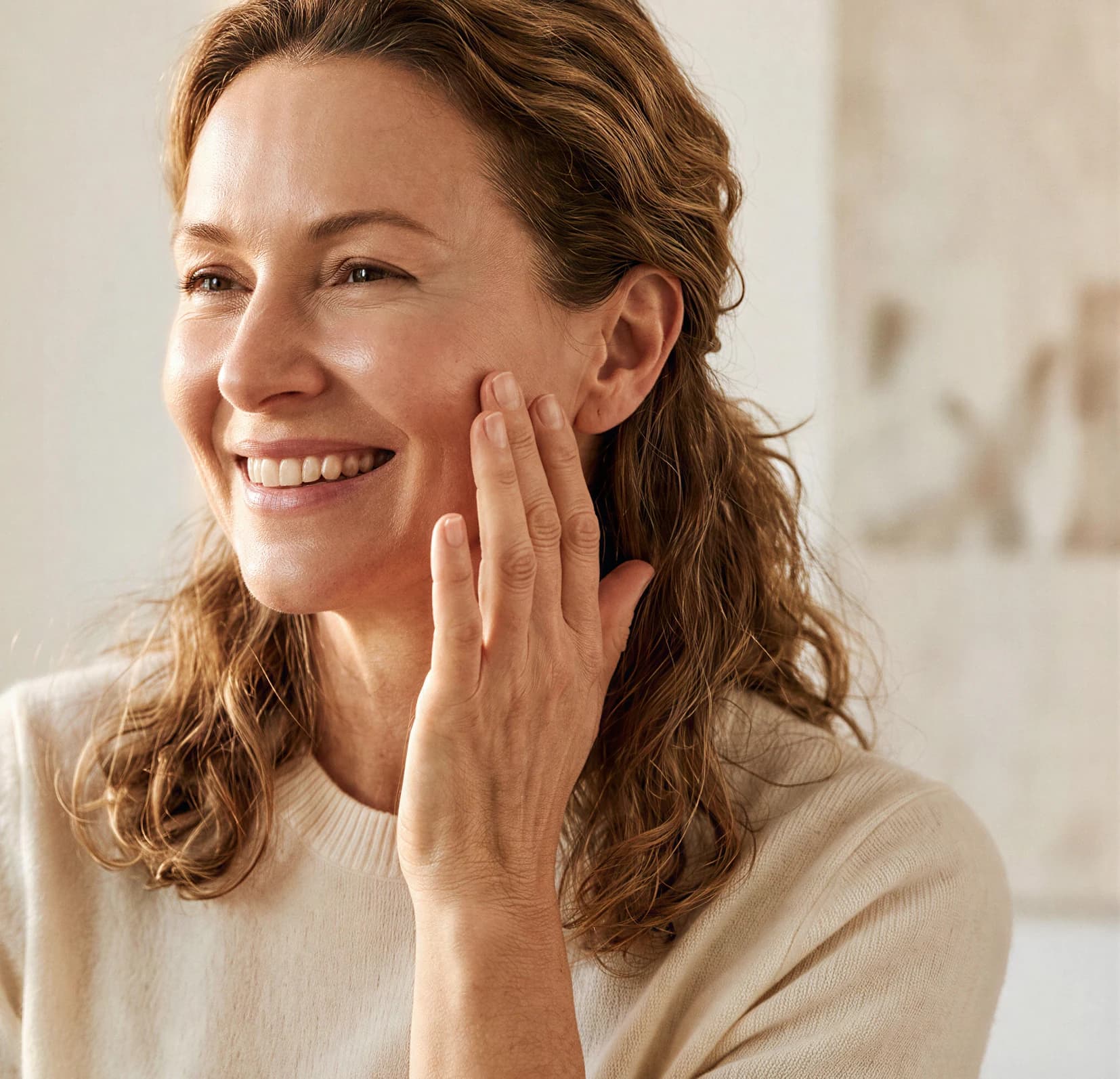 A smiling woman touching her cheek with radiant skin