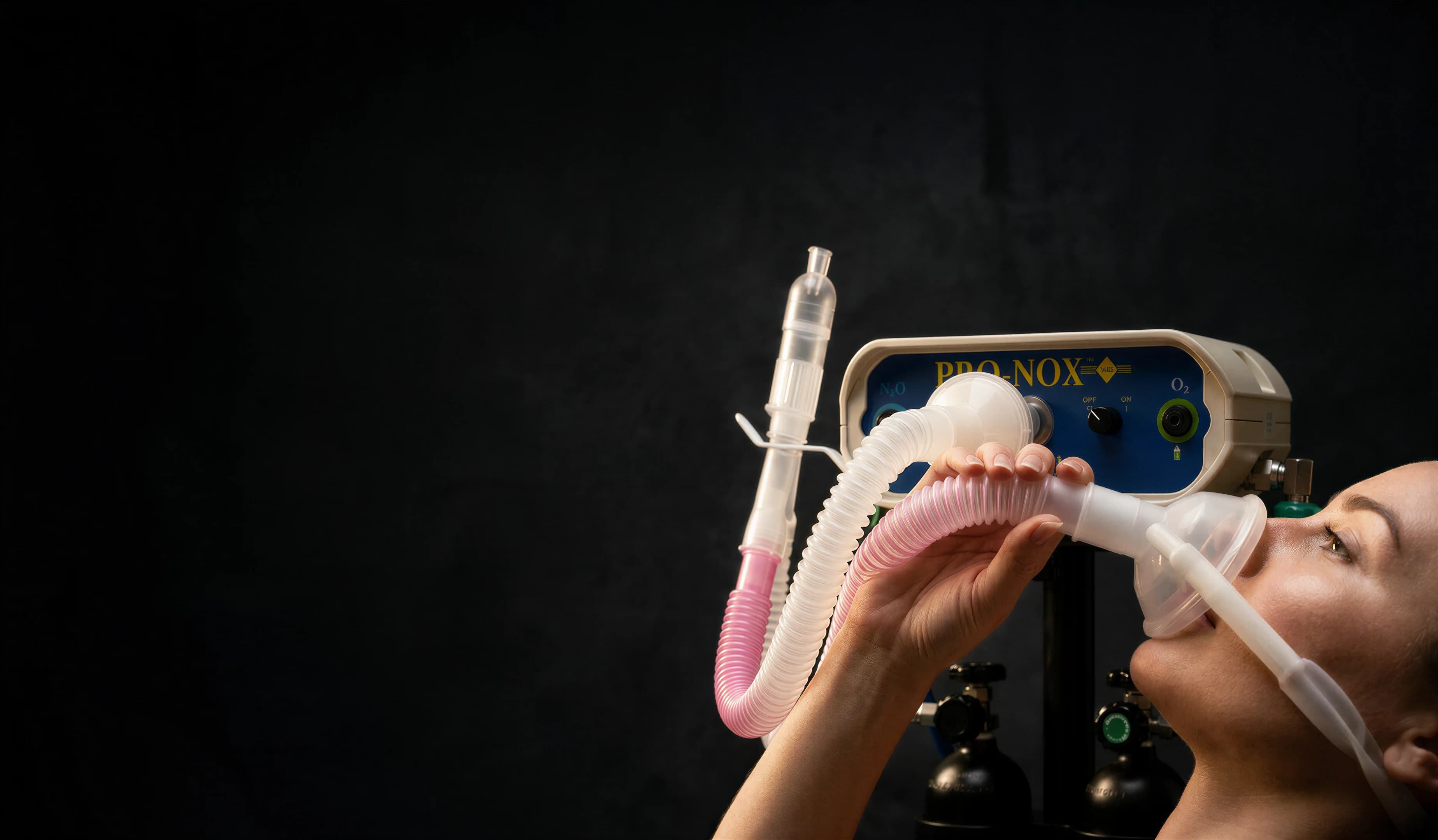 Hands holding the Pro-Nox breathing circuit and mask in front of the unit's control panel